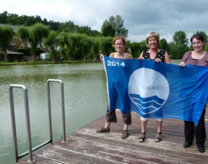 Anne Thibaut (Inter-environnement), Monique Jacob (échevine) et Cécile Zintz (Contrat rivière Semois-Chiers) présentent le Pavillon bleu. 